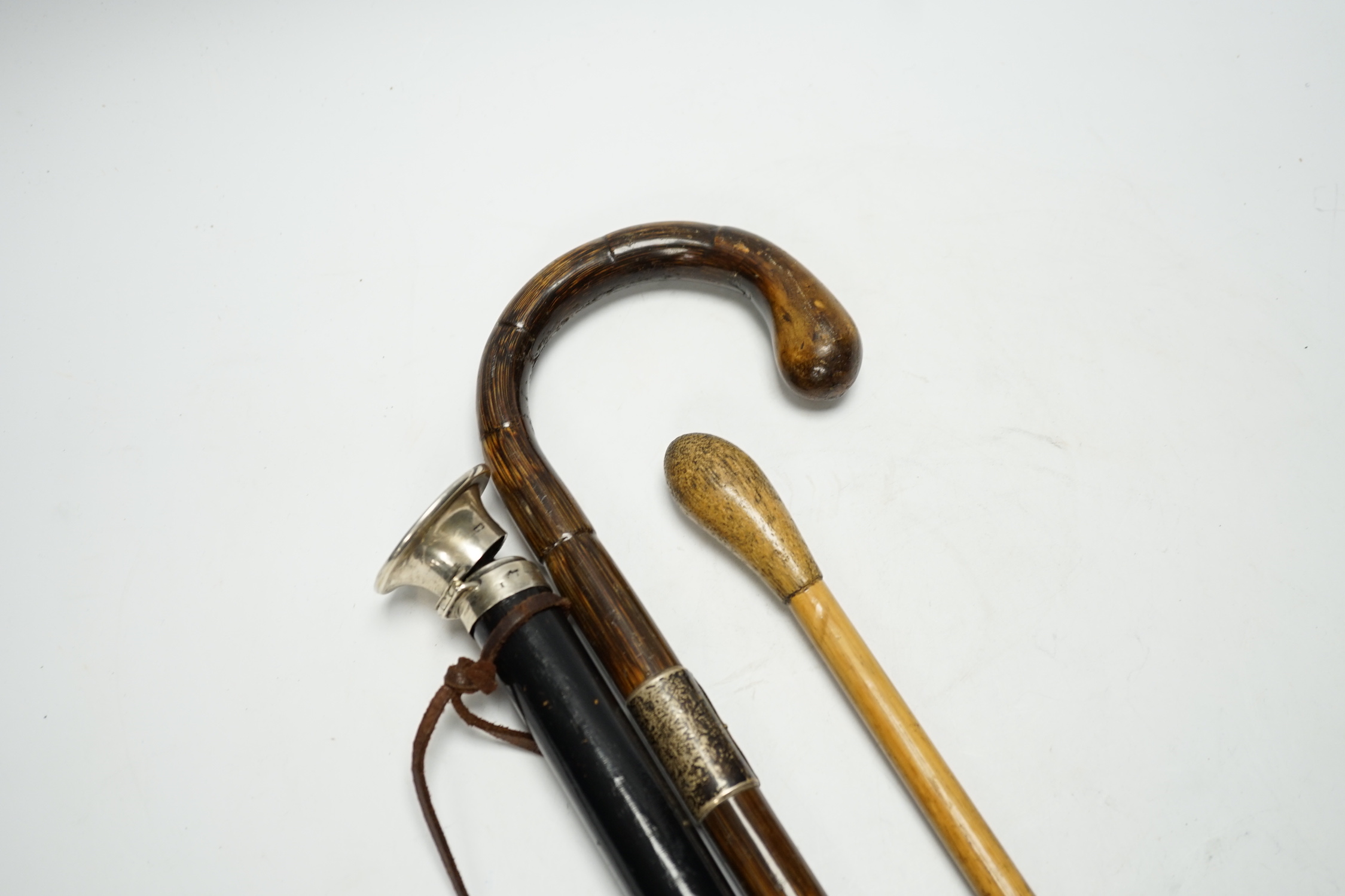 Three various walking canes including an inlaid tortoiseshell 'hidden compartment' cane, (two silver mounted), 90cm in length